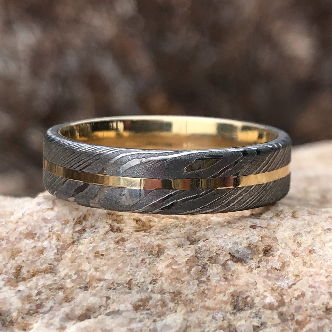 6mm wide white Damascus steel wedding band with a centered yellow gold inlay with a 14k yellow gold sleeve