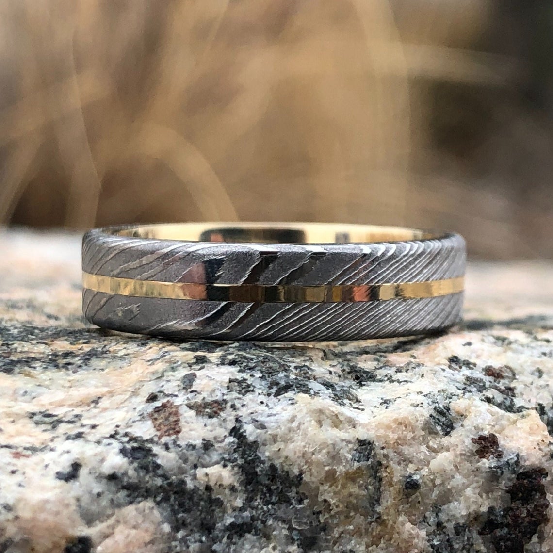 6mm wide white Damascus steel wedding band with a centered yellow gold inlay with a 14k yellow gold sleeve
